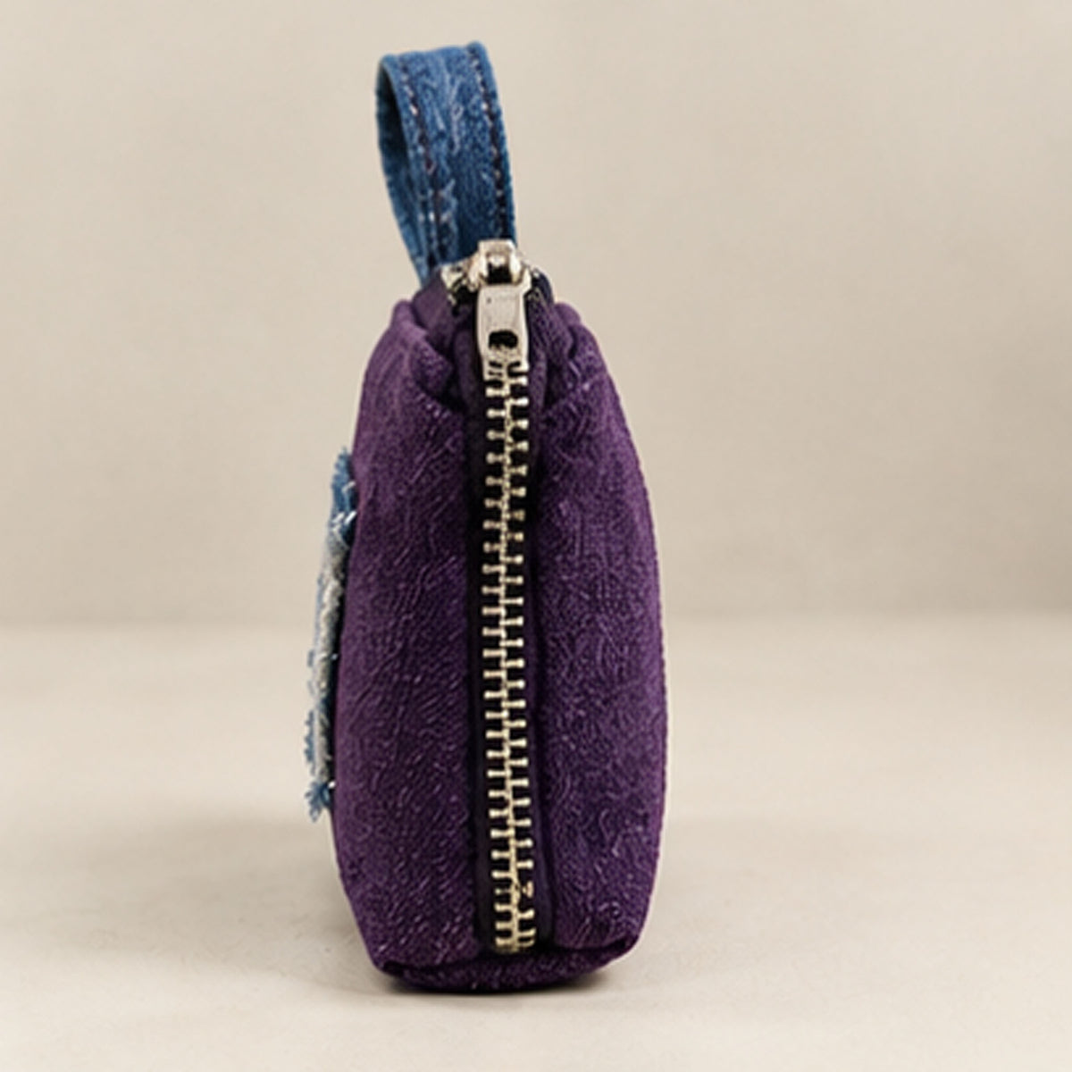 Lifestyle photo of purple denim-appliqué purse at a library table