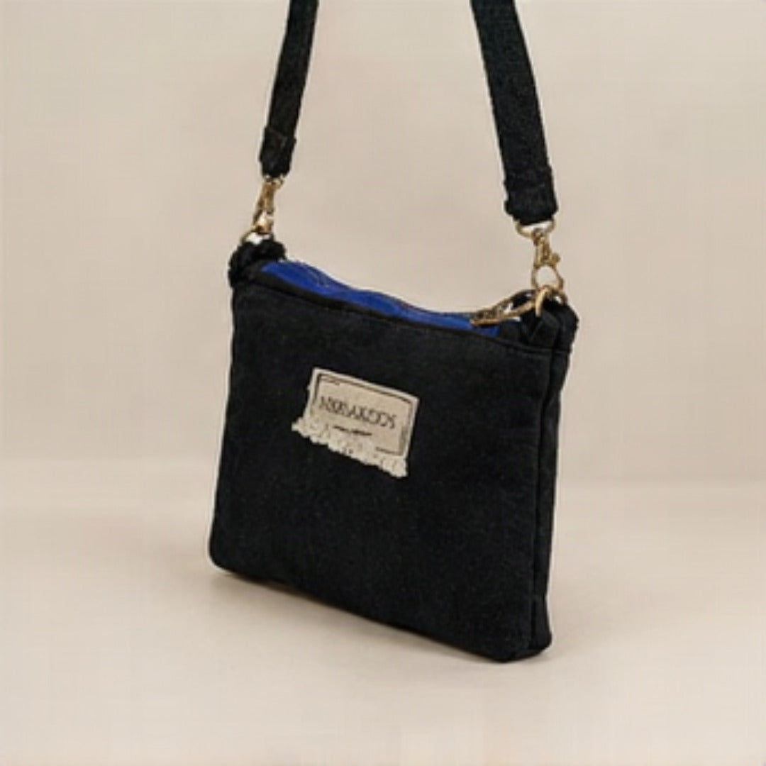 Nerakcos Black Denim Crossbody Bag - front view with frayed Nerakcos label, beige studio background