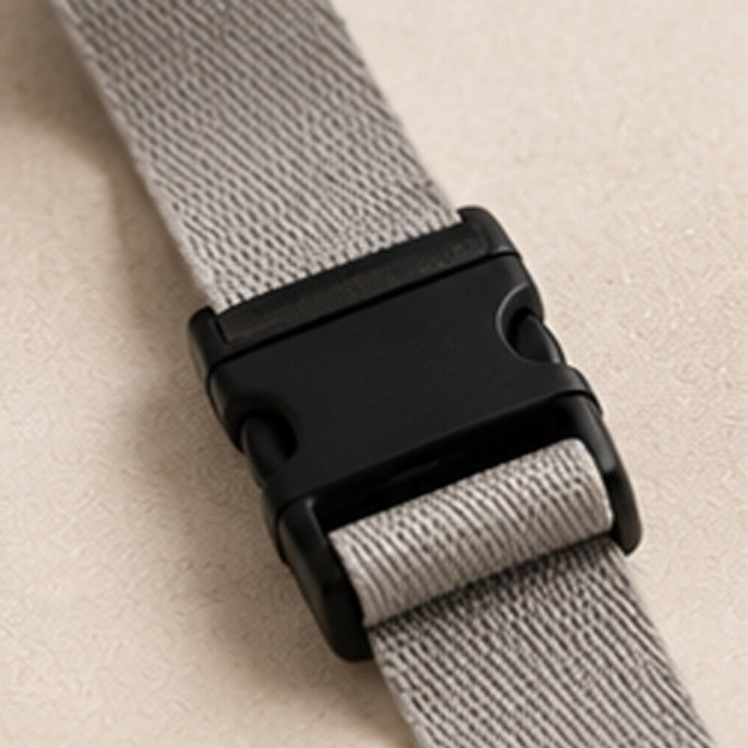 Close-up of matte black click-release buckle on grey adjustable webbing strap