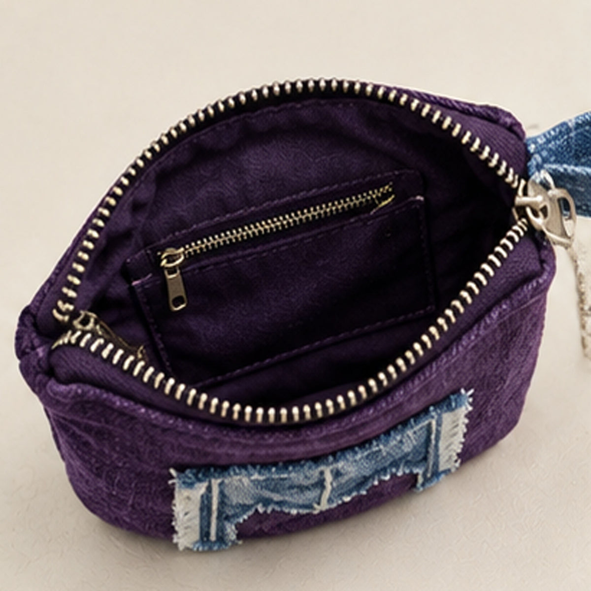 Side view of purple purse showing top zipper and denim loop