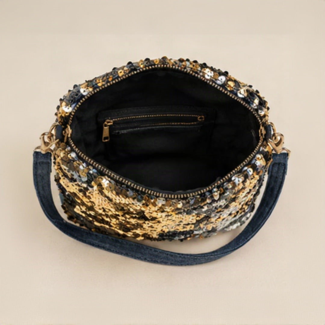Close-up of gold lobster clasp and D-ring hardware connecting navy denim strap to sequin body